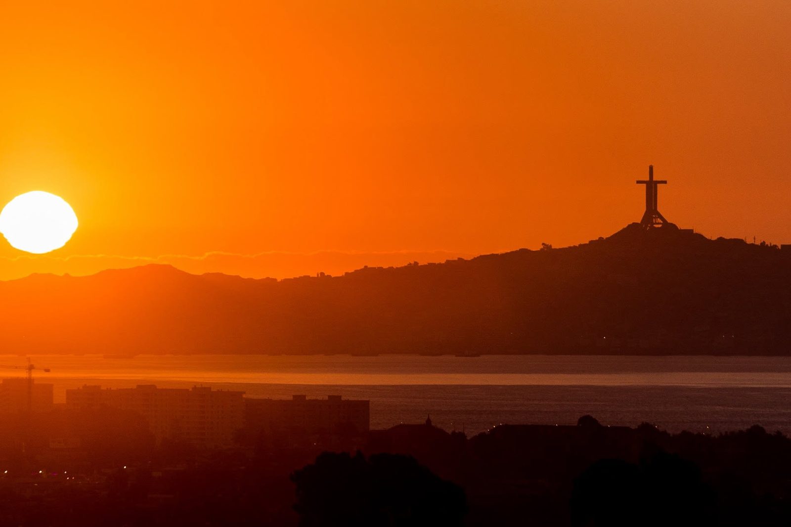 The sun setting over the bay at Coquimbo, with the Cruz del Tercer Milenio on the hill