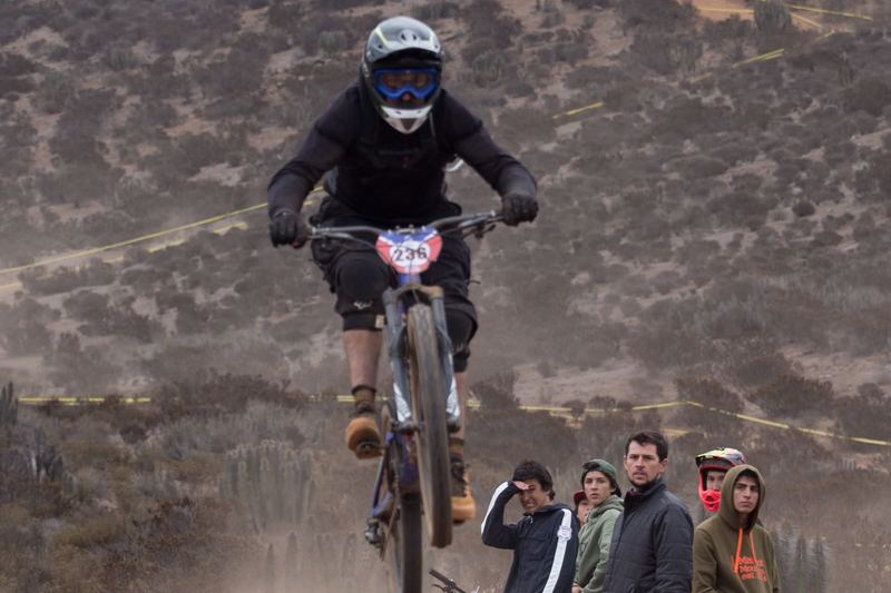 Mountain bike rider jumping a dirt kicker at an enduro race in Chile (photo 14 of 19)